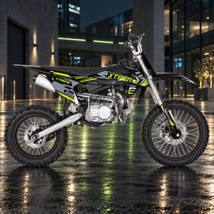 Highper DB608 Dirtbike 125ccm in Schwarz/Grün, seitenansicht rechts, vor beleuchteter Industriearchitektur auf nassem Asphalt.