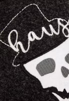 Nahaufnahme einer weißer Totenkopfstickerei, brauner Zigarre im Mund und Hausherr-Schriftzug auf schwarzem Filz