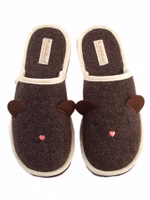 ein Paar dunkelbraune Filzpantoffeln mit niedlicher Stickerei eines Teddy-Gesichts und applizierten Filzohren. Außen hell eingefasst und dunkelbraune Innensohle