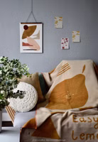 eine senfgelb- und beigefarbene Easy Peasy Kuscheldecke mit Zitronenmotiv und Schriftzug liegend auf einer Couch von petitsouridesign