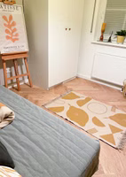 Adelheid X Anna Katharina Jansen Easy Peasy Teppich in einem Zimmer auf dem Boden liegend ein beige senffarbener "Easy peasy" Teppich mit abstraktem Zitronenmotiv
