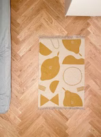 Easy Peasy Teppich 80 x 120 cm auf dem Boden liegend ein beige senffarbener "Easy peasy" Teppich mit abstraktem Zitronenmotiv