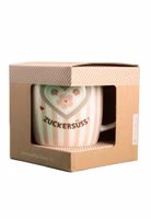in einer Verpackung mit Sichtfenster eine rosa cremeweiß gestreifte Henkeltasse aus Porzellan mit dem dunkelbraunen Schriftzug "Zuckersüss" und darüber ein großes Herz mit Blümchen