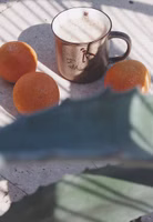in der Sonne stehend ein hellbrauner Henkelbecher aus Porzellan mit dunkelbraunem Schriftzug "Einfach mal abhängen" und einem Äffchen an der Becherkante hängend vorne. Becher innen weiß und ein kleines dunkelbraunes Kleeblatt seitlich