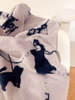 Nahaufnahme einer helllila-farbenen Kuscheldecke mit dem dunkelblauen Motiv von verschiedenen Hundebesitzern mit deren Hunden zum Teil an der Leine