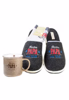 ein 3er Set bestehend aus einem Paar schwarzen Filzpantoffeln mit der weiß, rot und blauen Stickerei Bester Papa der Welt, ein Paar hellgraue Sportsocken sowie einem hellbraunen Henkelbecher Bester Papa