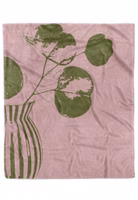 eine rosa Kuscheldecke mit dem olivgrünen, angeschnittenen Motiv eines Eukalyptus in einer gestreiften Vase