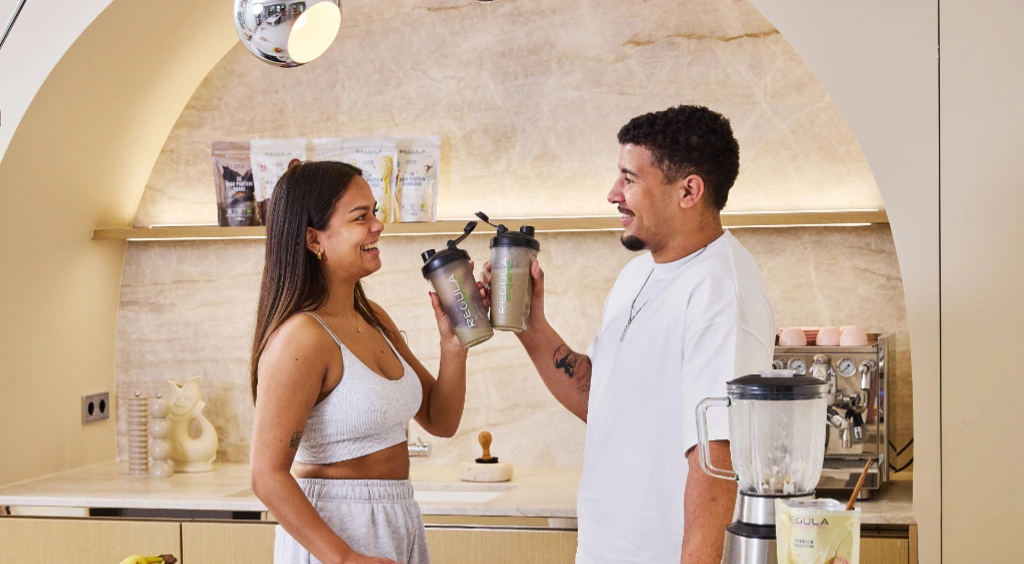 Mann und Frau stoßen mit zwei Protein Shakes an