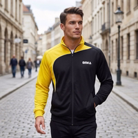 A man is walking down the street, wearing an OMKA tracksuit jacket with a stand-up collar. A subway sign is visible in the background.
