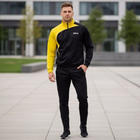 A man is standing outside, wearing a yellow-and-black OMKA tracksuit. A modern building complex is visible in the background.