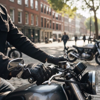 Close-up of leather and mesh motorcycle gloves on a rider's hands as he holds the handlebars of a motorcycle outdoors