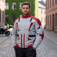 Cordura-Textil-Motorradjacken Herren steht auf der Straße, trägt Motorradjacke mit Protektoren. Motorräder im Hintergrund sichtbar.