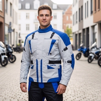 Cordura-Textil-Motorradjacken Herren steht auf der Straße, trägt Motorradjacke mit Protektoren. Motorräder im Hintergrund sichtbar.