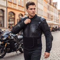 Herren in schwarzer Motorrad-Protektorenjacke auf einer Straße, im Hintergrund steht ein schwarzes Motorrad vor Gebäuden.