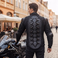 Rückansicht eines Herren in schwarzer Protektorenjacke neben einem Motorrad auf einer Straße vor Gebäuden.