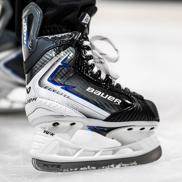BAUER Vapor FLYLITE Youth Schlittschuh – Detail auf dem Eis BAUER Vapor FLYLITE Youth Eishockey-Schlittschuh Schwarz Weiß Blau Detailaufnahme auf dem Eis